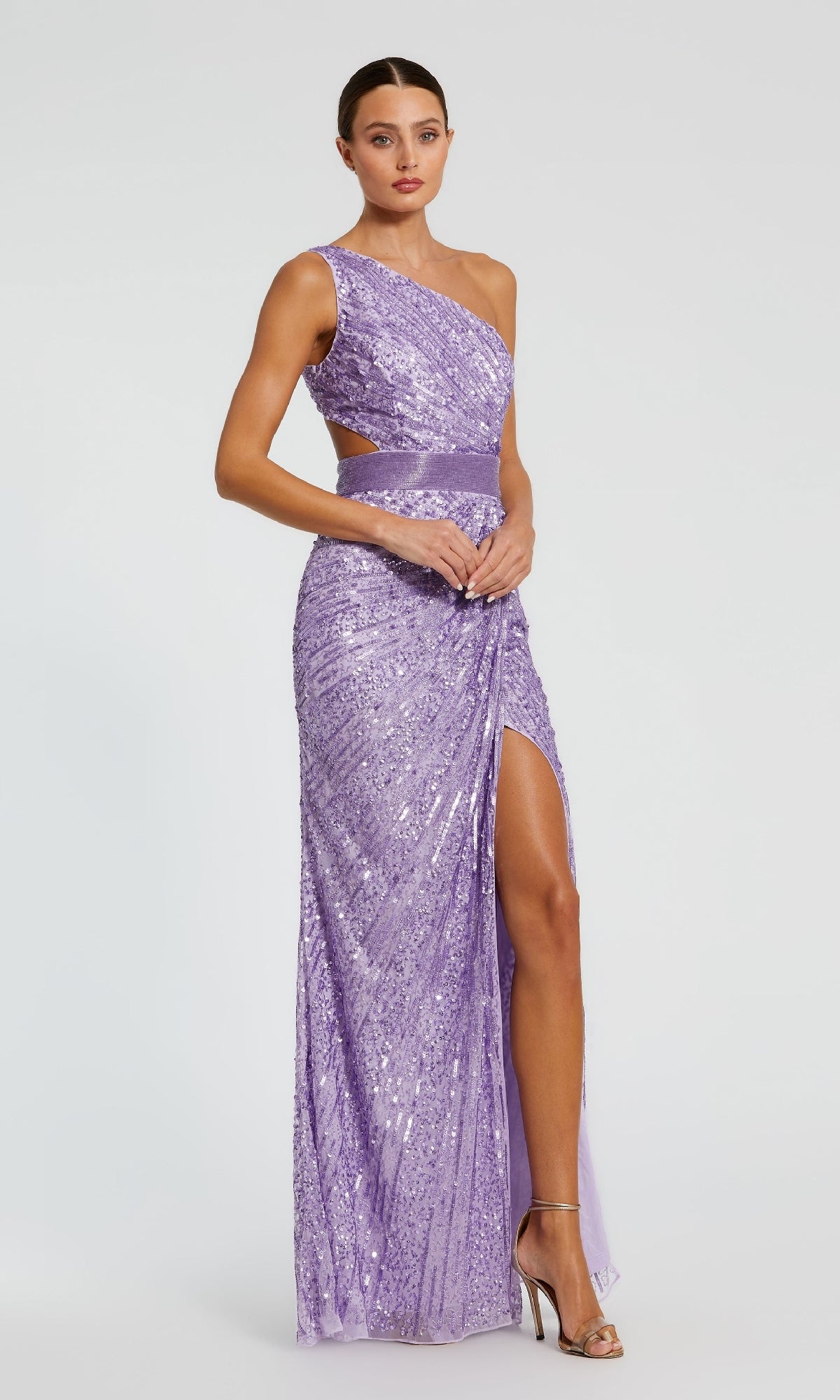 A woman models the Mac Duggal 5687, a one-shoulder lavender sequin formal dress with a side cutout and thigh-high slit, set against a plain light background.